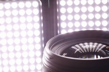 Ekipman kameramanı ve fotoğrafçı. Masadaki lensler parlak lambaların arka planına karşı. Kamera camının yansımasında parla ve bokeh.