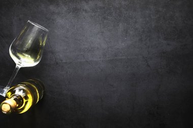 Masada bir bardak kırmızı şarap. Siyah şişe ve bir bardak şarap..