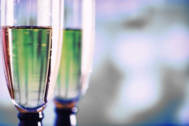 Köpüklü şaraplar için uzun bardaklı bir arka plan. Cam bardaklarda şampanya spreyi. Yansımalı kutlama içkisi.