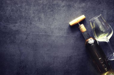 Masada bir bardak kırmızı şarap. Siyah şişe ve bir bardak şarap..