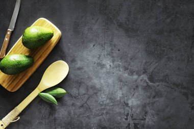 Avokado yemek tarifleri. Tahta kesme tahtasında servis edilen olgun yeşil avokado..