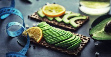 Avokado yemek tarifleri. Tahta kesme tahtasında servis edilen olgun yeşil avokado..