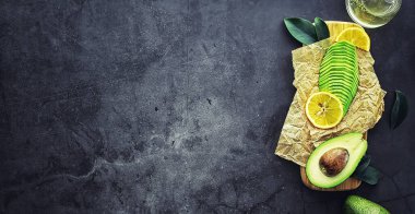 Avokado yemek tarifleri. Tahta kesme tahtasında servis edilen olgun yeşil avokado..