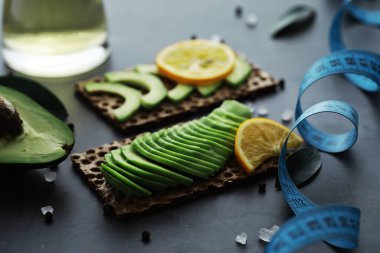 Avokado yemek tarifleri. Tahta kesme tahtasında servis edilen olgun yeşil avokado..