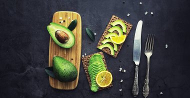 Avokado yemek tarifleri. Tahta kesme tahtasında servis edilen olgun yeşil avokado..