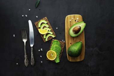 Avokado yemek tarifleri. Tahta kesme tahtasında servis edilen olgun yeşil avokado..