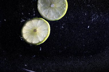 Olgun tatlı limonun üzerine su damlıyor. Metnin için kopyalama alanı olan taze kireç arkaplanı. Vejetaryen ve vejetaryen kavramı.