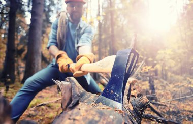 Ormanda ağaç kesen baltalı bir erkek işçi..