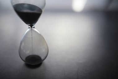 Zamanın akış konsepti. Karanlık bir arka planda kum saati. Yazma zamanı. Kelimenin yüzeyindeki gölge.