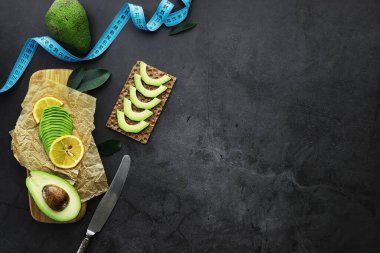 Avokado yemek tarifleri. Tahta kesme tahtasında servis edilen olgun yeşil avokado..