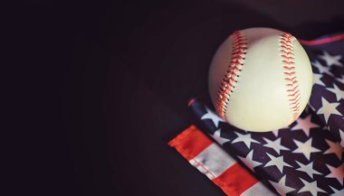 Amerikan geleneksel spor oyunu. Beyzbol mu? Kavram. Amerikan bayrağıyla birlikte beyzbol topu ve sopalar masada..