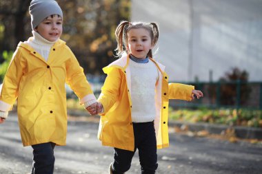 Çocuklar sonbaharda sonbahar parkında yürür