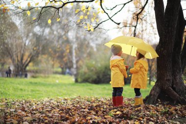 Çocuklar sonbaharda sonbahar parkında yürür