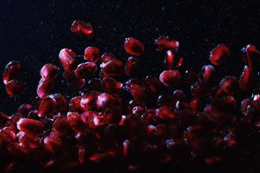 Olgun tatlı nar tohumlarına su damlaları düşer. Metnin için kopyalama alanı olan taze nar arkaplanı. Vejetaryen ve vejetaryen kavramı.