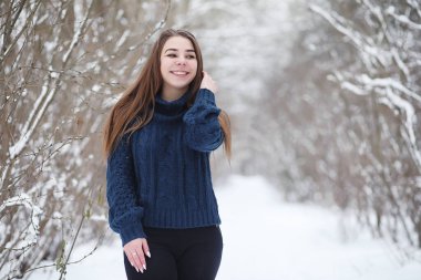 Kış parkında yürüyüş yapan genç bir kız. Kış ormanlarında Noel tatili. Kız parkta kışın tadını çıkarıyor.