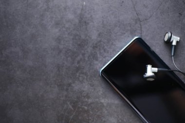 Cep telefonu ve kulaklıklar masada. Başlarken müzik dinle. Çevrimiçi oyuncu. Akıllı telefonlar için ses uygulamaları.
