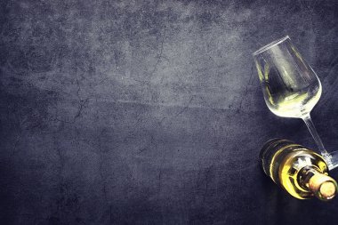 Masada bir bardak kırmızı şarap. Siyah şişe ve bir bardak şarap..