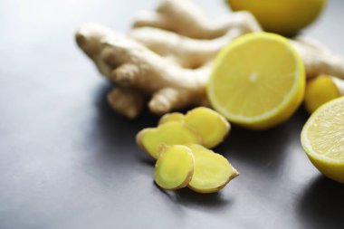 Zencefil kökü bütün ve dilimlenmiş. Koyu arkaplanda limonlu zencefil çayı. Taş zeminde taze zencefil kökü. Vitaminler. Üst Manzara. Metnin için boş yer.