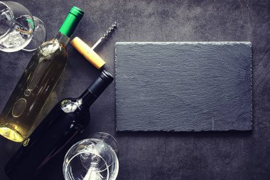 Masada bir bardak kırmızı şarap. Siyah şişe ve bir bardak şarap..