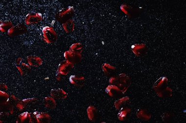 Olgun tatlı nar tohumlarına su damlaları düşer. Metnin için kopyalama alanı olan taze nar arkaplanı. Vejetaryen ve vejetaryen kavramı.