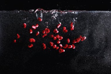 Olgun tatlı nar tohumlarına su damlaları düşer. Metnin için kopyalama alanı olan taze nar arkaplanı. Vejetaryen ve vejetaryen kavramı.