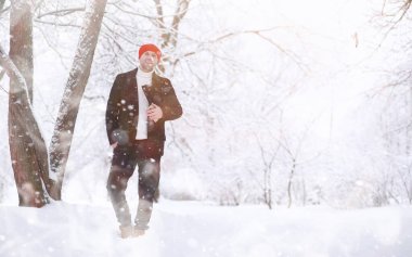 Parkta yürüyen bir adam. Kışın kar altında şemsiyeli genç bir adam..