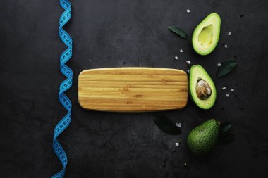 Avokado yemek tarifleri. Tahta kesme tahtasında servis edilen olgun yeşil avokado..