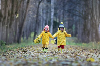 Küçük çocuklar yaprakları sonbaharda sonbahar parkta yürüyorlar
