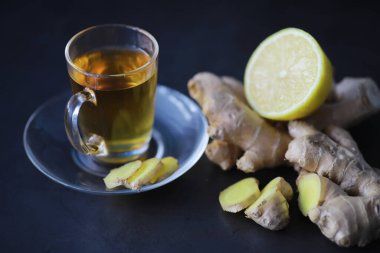 Zencefil kökü bütün ve dilimlenmiş. Koyu arkaplanda limonlu zencefil çayı. Taş zeminde taze zencefil kökü. Vitaminler. Üst Manzara. Metnin için boş yer.