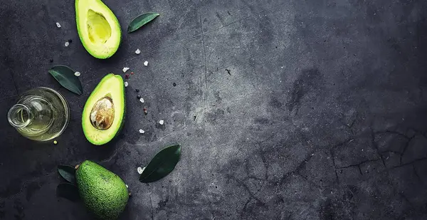 Avokado yemek tarifleri. Tahta kesme tahtasında servis edilen olgun yeşil avokado..