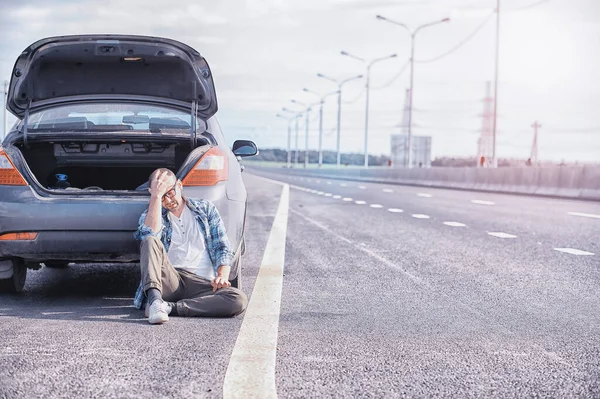 道路上の車のホイールを交換します タイヤの仕事をしてる男が — ストック写真