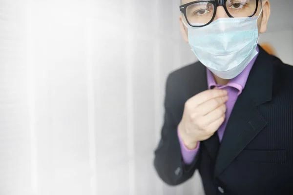 A disposable medical mask sticks out of a pocket instead napkin. A man with a disposable mask in a suit and jeans. Individual respiratory protection.