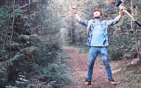 Male lumberjack in the forest. Professional woodcutter inspects trees for felling.