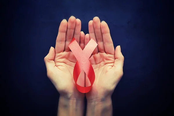 Symbol of human immunodeficiency virus disease. Red ribbon. A helping hand and support. Background.