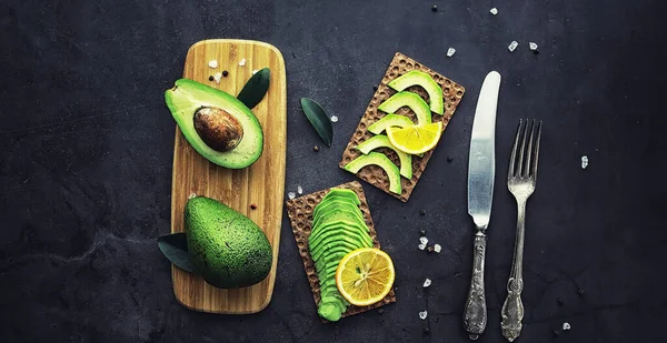 Avokado yemek tarifleri. Tahta kesme tahtasında servis edilen olgun yeşil avokado..