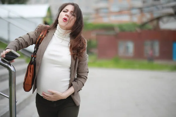 妊娠中の女性は日中通りの腹部の痛みを感じる — ストック写真