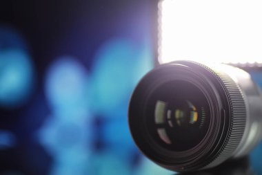 Ekipman kameramanı ve fotoğrafçı. Masadaki lensler parlak lambaların arka planına karşı. Kamera camının yansımasında parla ve bokeh.