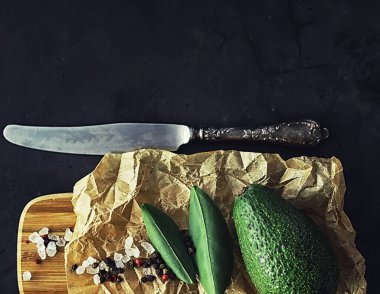 Avokado yemek tarifleri. Tahta kesme tahtasında servis edilen olgun yeşil avokado..