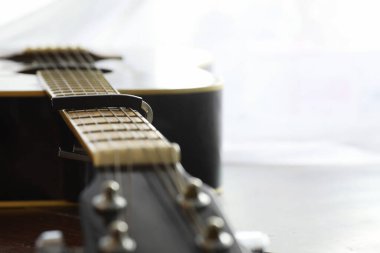 Sahnede telli bir enstrüman çalan sanatçı için akustik gitar. Capo 'lu siyah gitar. Müzik arkaplanı.