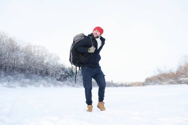 Bir adam sırt çantasıyla seyahat eder. Ormanda kış yürüyüşü. Kışın parkta yürüyüş yapan bir turist..