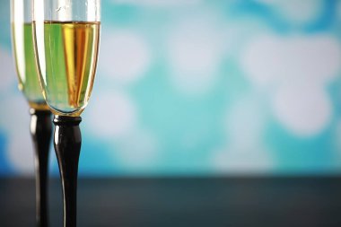 Köpüklü şaraplar için uzun bardaklı bir arka plan. Cam bardaklarda şampanya spreyi. Yansımalı kutlama içkisi.