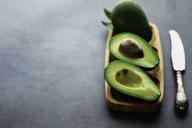 Avokado yemek tarifleri. Tahta kesme tahtasında servis edilen olgun yeşil avokado..