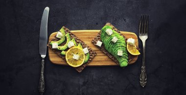 Avokado yemek tarifleri. Tahta kesme tahtasında servis edilen olgun yeşil avokado..