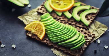 Avokado yemek tarifleri. Tahta kesme tahtasında servis edilen olgun yeşil avokado..