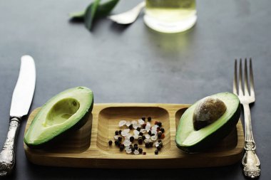 Avokado yemek tarifleri. Tahta kesme tahtasında servis edilen olgun yeşil avokado..