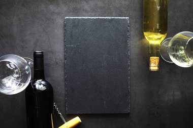 Masada bir bardak kırmızı şarap. Siyah şişe ve bir bardak şarap..