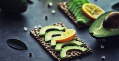 Avokado yemek tarifleri. Tahta kesme tahtasında servis edilen olgun yeşil avokado..