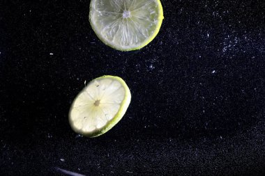 Olgun tatlı limonun üzerine su damlıyor. Metnin için kopyalama alanı olan taze kireç arkaplanı. Vejetaryen ve vejetaryen kavramı.