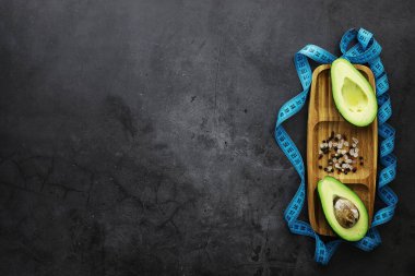 Avokado yemek tarifleri. Tahta kesme tahtasında servis edilen olgun yeşil avokado..