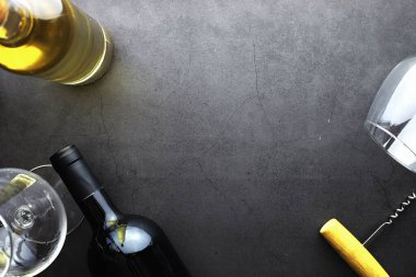 Masada bir bardak kırmızı şarap. Siyah şişe ve bir bardak şarap..